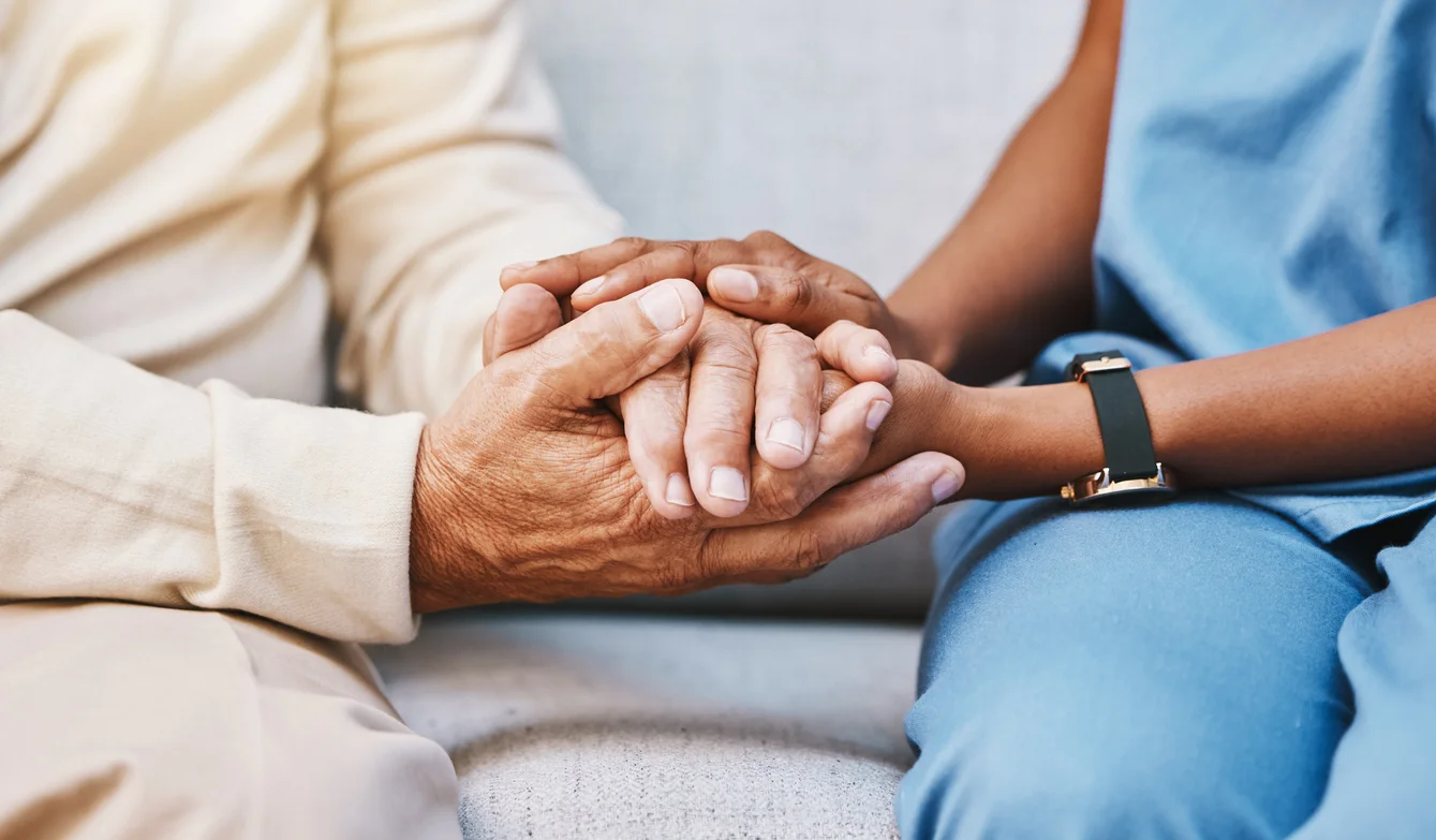 nurse holding a senior hand and giving support